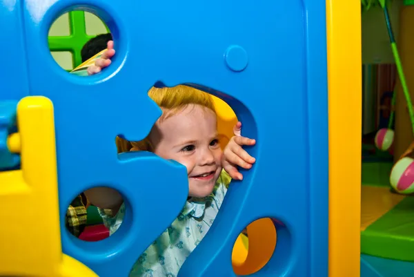 Girl 1,5 years old peeps out through the holes of game complex — Stock Photo, Image