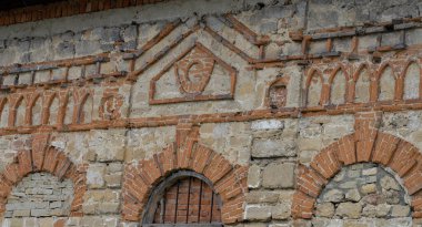 Kıvırcık tuğla işi, gri üzerine kırmızı tuğla. Kapalı pencere açıkları olan bir ortaçağ evinin duvarı. Gümrük binası, ilk olarak 15. yüzyılda bahsedildi.