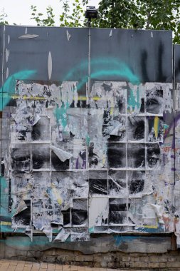 Çitin reklam posterleri asılmış bir bölümü, zaman ve atmosferik etkilerin etkisiyle anlamsal amaçlarını yitirdiler.