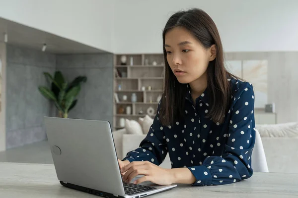 Mujer de negocios asiática empresaria con una camisa oscura y gafas, usando una computadora, mirando una pantalla, trabajando en un escritorio de oficina, sonriendo mujer profesional asiática escribiendo correo electrónico en un ordenador portátil en el — Foto de Stock