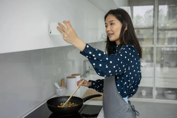 Joven bloguera asiática e influenciadora en línea, grabando contenido de video sobre comer sano, freír verduras en una sartén — Foto de Stock