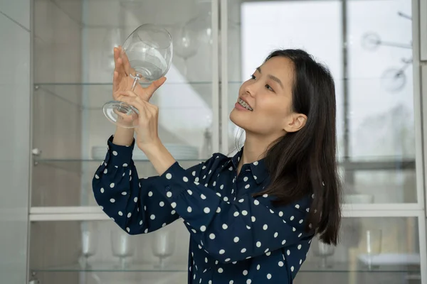 Женщина берет стакан из посудомоечной машины, стоя на кухне — стоковое фото