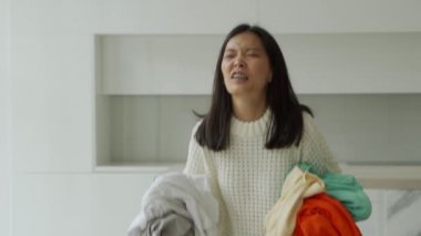 Saldırgan Asyalı kadın iç çamaşırını havaya fırlatıyor. Ev temizliği ve çamaşır konsepti.