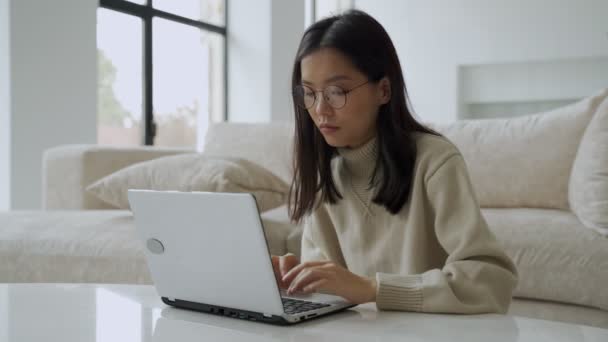 Gözlüklü başarılı bir Asyalı iş kadını bilgisayarında bir dizüstü bilgisayarla başarıdan zevk alır. Zaferini kutlayan bir ikramiye almış neşeli bir kadın.. — Stok video