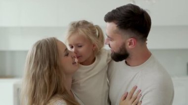 Güzel genç bir aile, bir anne ve sakallı bir baba güzel kızlarını kollarında tutuyorlar.