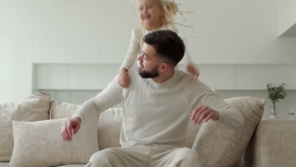 Active joyful young single father holding a happy laughing girl daughter on his shoulder, showing flight with his hands — Stock Video