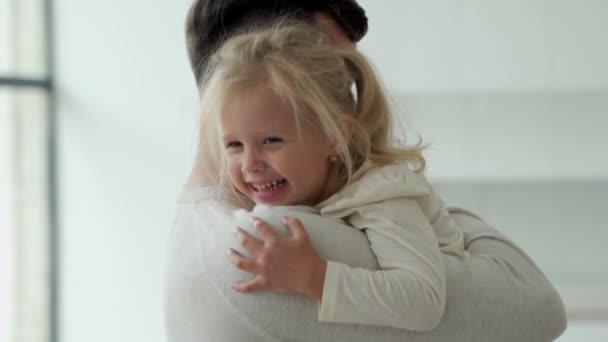 Portrait of a cute little girl in her fathers arms. A father and his daughter, a baby girl, play cuddling. — Stock Video