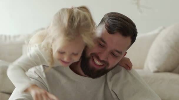 Vater liest seiner kleinen Tochter ein Buch vor, während sie im Schlafzimmer auf dem Boden liegt — Stockvideo