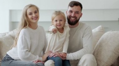 Küçük kız elinde yeni bir aile evinin anahtarlarını tutuyor. Gülümseyen genç bir çiftin portresi ve anahtarları gösteren sevimli bir kız.