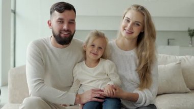 Güzel, genç ve neşeli bir aile evinde kanepede oturuyor, gülüyor ve birbirleriyle oynuyorlar..
