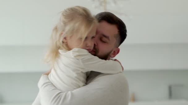 Glücklicher Vater küsst seine kleine Tochter zu Hause im Wohnzimmer. — Stockvideo