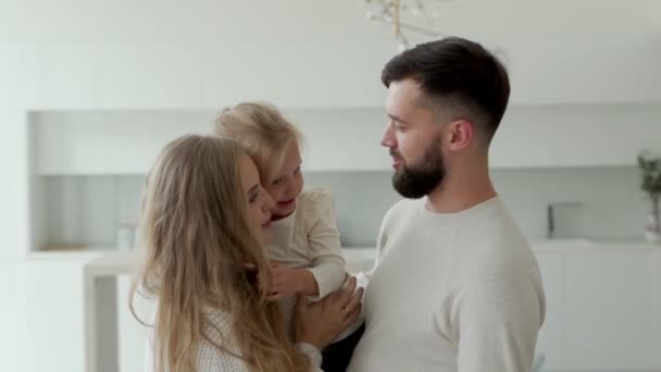 Schöne junge Familie, eine Mutter und ein bärtiger Vater halten ihre kleine schöne Tochter im Arm — Stockvideo