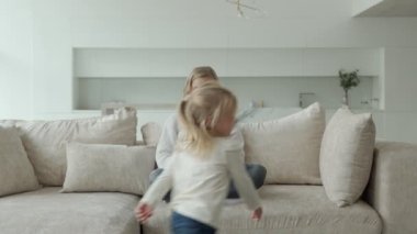 Kadın girişimci, kızı oynarken ve annesinin çalışmasını engellerken kanepede dizüstü bilgisayarla çalışmaya odaklanmış.