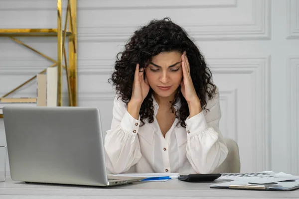 India creativa rizado mujer de pelo negro cubre su cara con la mano y se molesta de trabajar delante de un ordenador portátil en un escritorio en la oficina, concepto de estilo de vida de la oficina — Foto de Stock