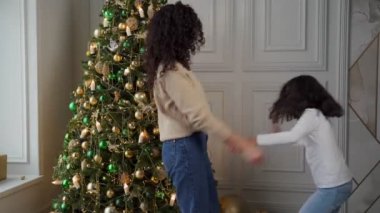 Genç anne küçük kızıyla bir Noel ağacının arkasında dans ediyor.