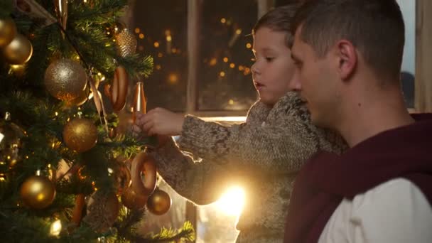 Apa és fia díszítik a karácsonyfát. Karácsonyi dekoráció. A családi nyaralás fogalma. — Stock videók