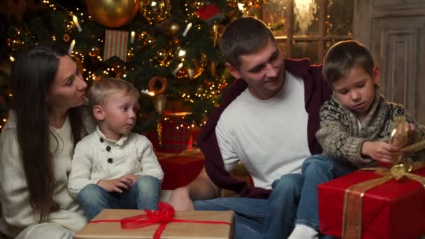 Familieportret van Kerstmis - familie zit op de vloer voor een prachtige kerstboom. — Stockvideo