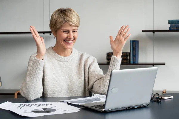 Mujer de mediana edad en el momento de la victoria cuando utiliza su computadora portátil en una oficina moderna — Foto de Stock