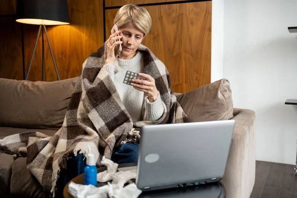 Telesalud - una mujer de mediana edad que está enferma de chat de vídeo con el médico en el ordenador portátil en casa — Foto de Stock