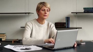 Modern bir ofiste dizüstü bilgisayarını kullandığında zafer anında orta yaşlı bir iş kadını.