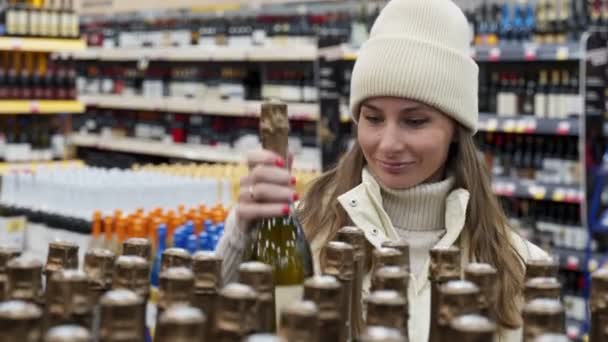 A young woman shopping in a supermarket, in a grocery store, buying a bottle of champagne — Stock Video