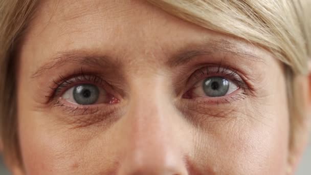 50 세의 한 중년 여성 이 카메라, 노화 방지 피부 관리, 미 (美), 성형수술, 미용 시술등을 들여다보고 있습니다. 얼굴을 클로즈업 — 비디오