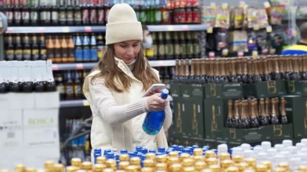 Uma jovem mulher comprando em um supermercado, em uma mercearia, comprando uma garrafa de champanhe — Vídeo de Stock