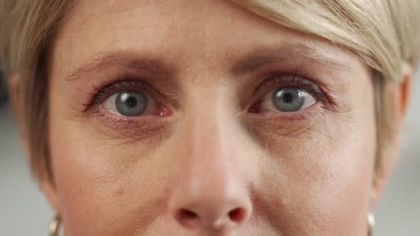 Een 50-jarige vrouw van middelbare leeftijd kijkt in de camera, anti-aging huidverzorging, schoonheid, plastische chirurgie, cosmetische procedures. Close-up van het gezicht — Stockvideo