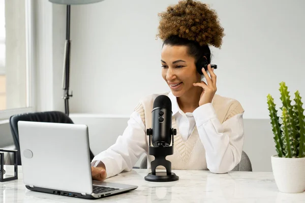 Mujer negra joven está haciendo una grabación de podcast en línea para su programa en línea. Una atractiva mujer de negocios afroamericana hablando en un micrófono para un programa de radio. — Foto de Stock