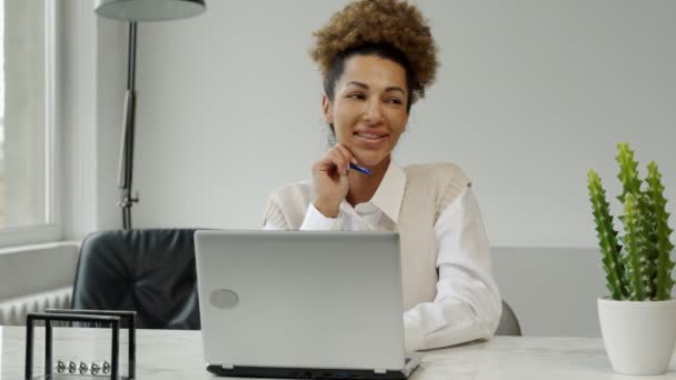 Portret troskliwej biznesowej czarnej kobiety siedzącej przy stole z laptopem i patrzącej w dal — Wideo stockowe
