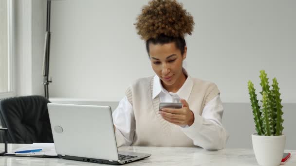拿着信用卡的非洲裔美国女人，坐在桌子旁，带着笔记本电脑，上网购物，还在网上付款 — 图库视频影像