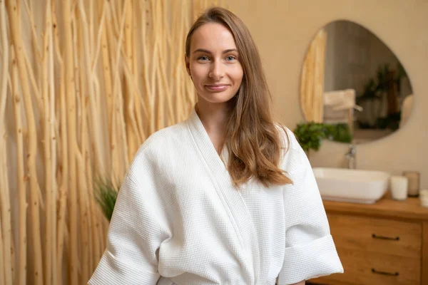 Young woman in a housecoat in the bathroom, looking at the camera. — Stockfoto