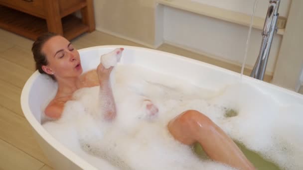 Uvolněná krásná mladá žena si dává bublinkovou koupel — Stock video