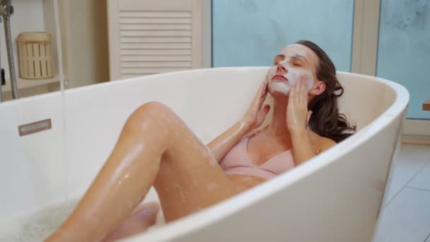 Giovane ragazza applica uno scrub viso per la pelle mentre seduto in bagno — Video Stock