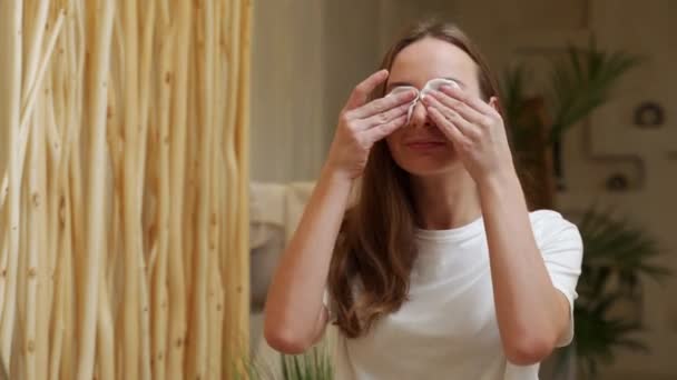 Young woman using cotton pad while cleaning her face in the bathroom — Stockvideo