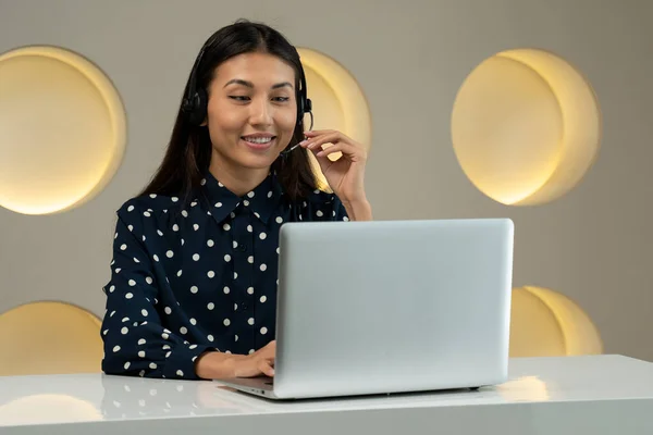 Mujer asiática sonriente con auriculares, trabajando en la oficina como servicio de atención al cliente, sentada en la oficina — Foto de Stock