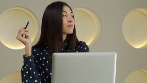 Thoughtful business Asian woman working at a computer, smiling and looking into the distance, thinking about a successful business — Vídeo de Stock