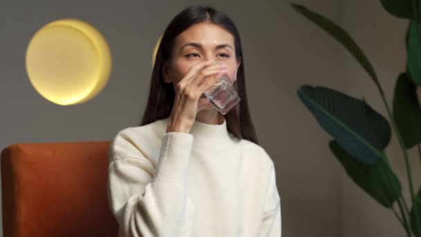 Young asian woman drinking water. Smiling female model holding transparent glass in her hand. — ストック動画