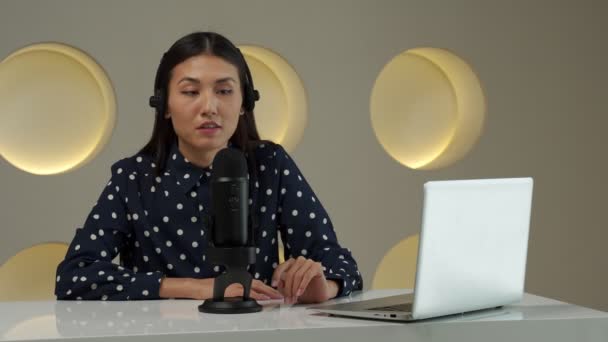 Asian woman recording a podcast on laptop computer with microphone while online live streaming — Wideo stockowe
