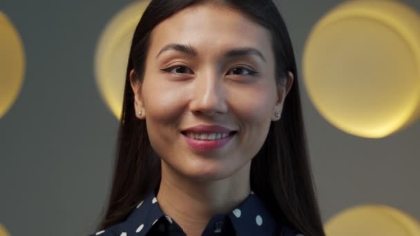 A close-up portrait of a young charming Asian woman with fresh skin. She looks thoughtfully at the camera — Wideo stockowe