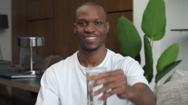 Красивий молодий чорний чоловік тримає склянку свіжої прохолодної води в руках — стокове відео