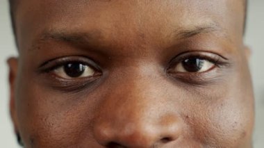 Gözleri dik bakan siyah bir adamın yakın çekimi. Kameraya bakan gülümseyen bir adamın portresi..