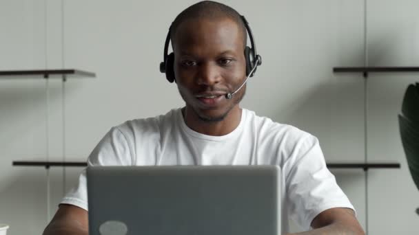 Een zwarte man is een klantenserviceoperator met een handsfree headset die in een kantoor werkt. — Stockvideo