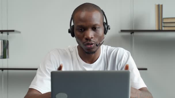 Ein lächelnder schwarzer Mann mit einem Headset lernt eine Fremdsprache per Videoanruf — Stockvideo