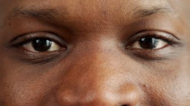 Gözleri dik bakan siyah bir adamın yakın çekimi. Kameraya bakan gülümseyen bir adamın portresi..