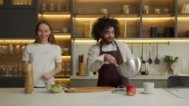 Mutlu Arap erkek aşçı ve kadın dans edip salata pişiriyor.