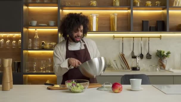 Fröhlicher muslimischer Männerkoch kocht Salat, der am Tisch tanzt — Stockvideo