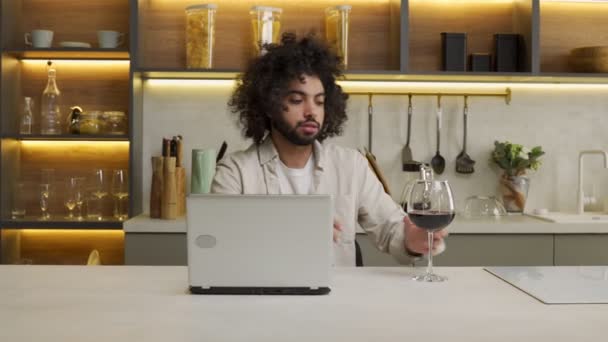 Arap adam dizüstü bilgisayarda çalışıyor ve şarap içiyor. — Stok video