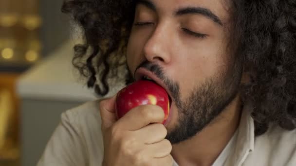 Arabisch mann mit verdorben haar genießt essen apfel im küche — Stockvideo