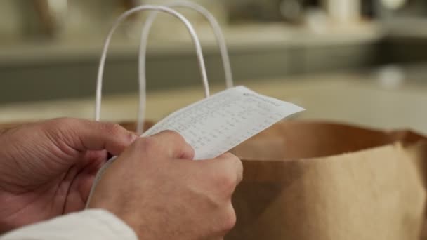 Mann sieht Kontrolle nach Einkauf im Lebensmittelgeschäft zu Hause an — Stockvideo